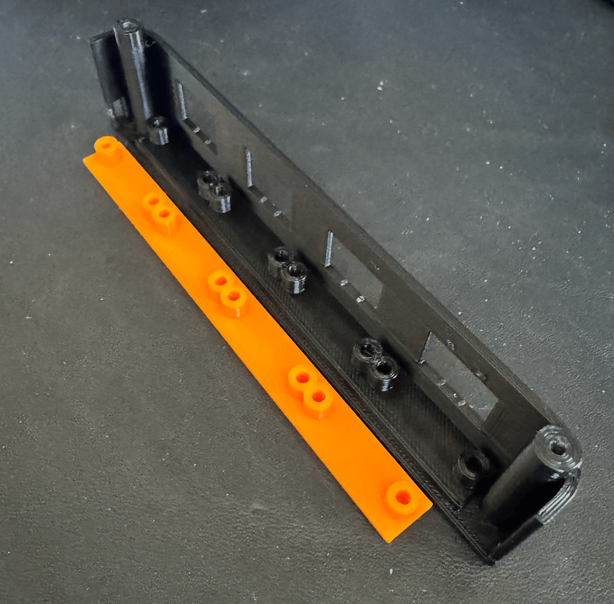 PCB mounting rail separated next to the original test front panel with the rail printed in place